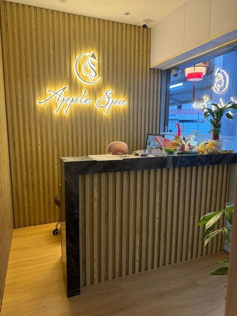 Apple Spa reception desk with warm neon signage and wood-slat feature wall
